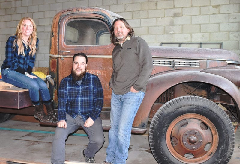 From left: Katie Flanagan, Chris Detrick, and Mark Medura sitting on a 1946 Chevy farm truck that will serve as a stage at Level Crossing Brewing.